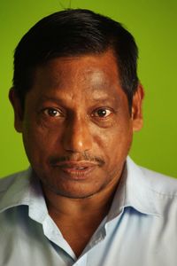 Close-up portrait of mature man standing against green curtain