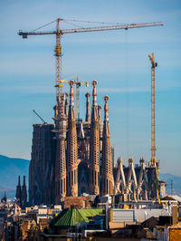 Cranes at construction site against sky in city