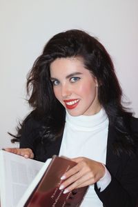 Portrait of young woman using book at home