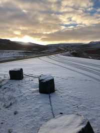 Scenic view of snow covered field against sky during sunset
