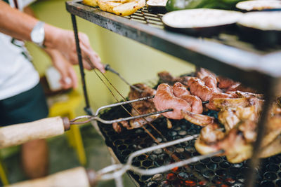 Midsection of man preparing meat on barbecue grill