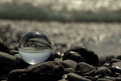 Close-up of crystal ball and stones on beach