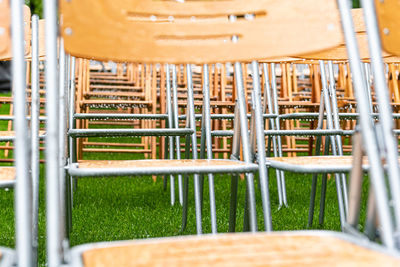 Wooden chairs stand outside in the park. empty auditorium, green grass, trees, water drops.
