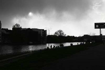 View of city at waterfront against cloudy sky