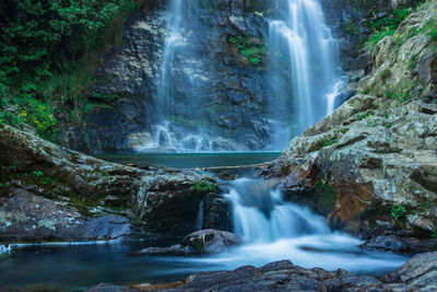Waterfall flowing streams through rocks in forest with blurred water surface long exposure shot