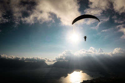 Silhouette person paragliding against sky