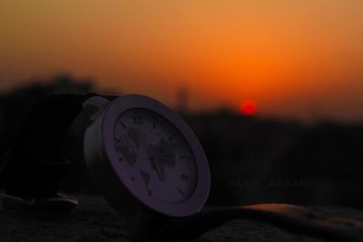 Close-up of clock against sky at sunset