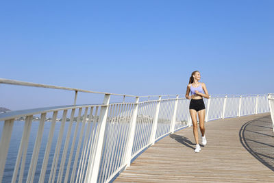 Happy young woman jogging on elevated walkway