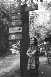 Full length of woman standing by sign on tree