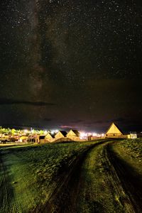 Road amidst field against sky at night