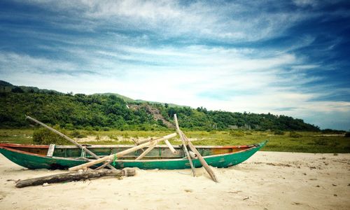 Boat moored on beach against sky