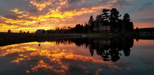 Scenic view of lake against cloudy sky during sunset
