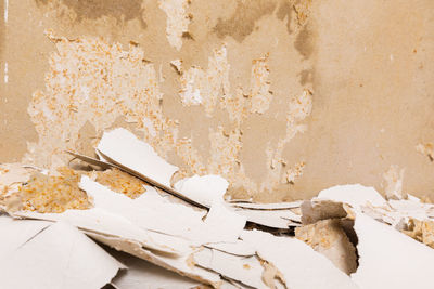 Close-up of broken glass on table against wall