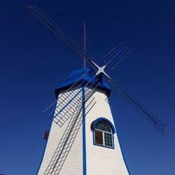 Low angle view of traditional windmill against clear blue sky