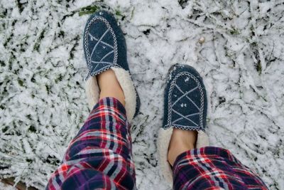 Low section of woman standing on snow covered field