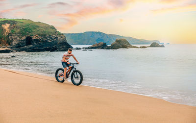 Young man riding a fat bike on the beach