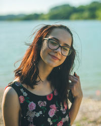 Portrait of young woman wearing sunglasses standing at beach