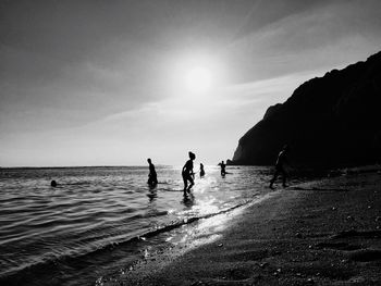 Silhouette people on beach against sky