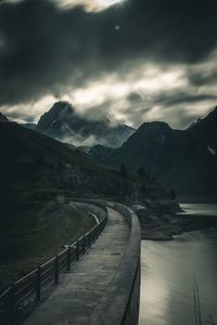 Empty road leading towards mountains against sky