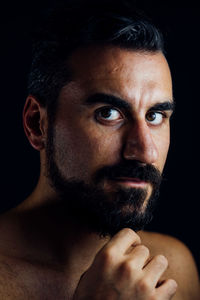 Close-up portrait of shirtless man against black background