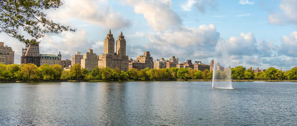 Buildings by river against sky