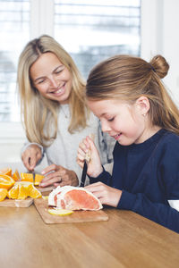 Mother and daughter playing with fruits at home