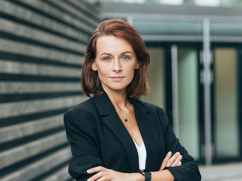 Portrait of young woman standing against wall