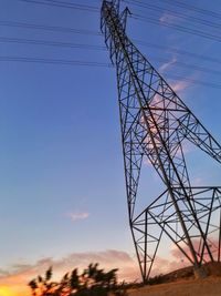 Low angle view of electricity pylon against blue sky