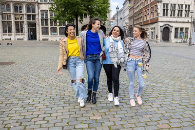 Portrait of smiling friends walking on street