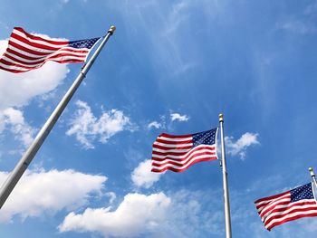 Low angle view of american flags against sky