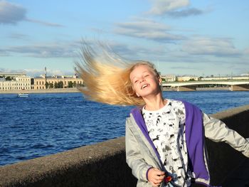 Girl tossing hair while standing against river