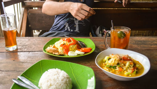 Close-up of man having indonesian breakfast food on table