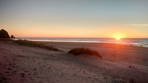 Scenic view of beach against clear sky during sunset