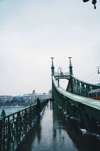 Young man on bridge over river in city against sky