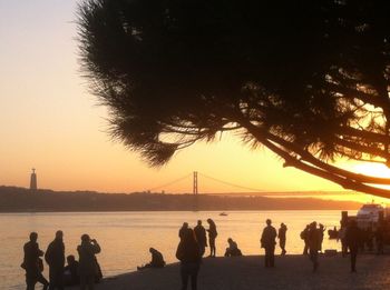 Silhouette people standing on beach against clear sky during sunset