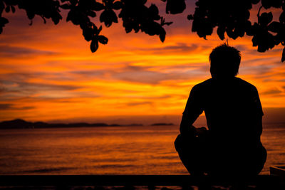 Silhouette man on beach against orange sky