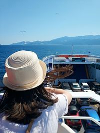 Rear view of woman wearing hat while sitting in boat at sea