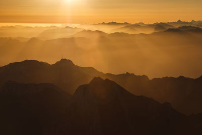 Scenic view of mountains in foggy weather during sunset