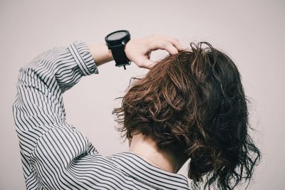 Rear view of woman with hand in hair against white background