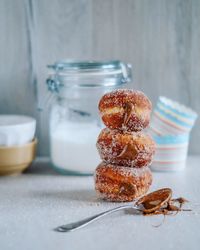 Stacked donuts by spoon on table at home