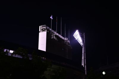 Low angle view of illuminated floodlight at stadium against sky