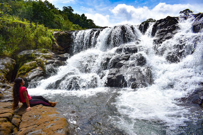 Rear view of man standing in waterfall