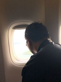 Portrait of man looking through airplane window