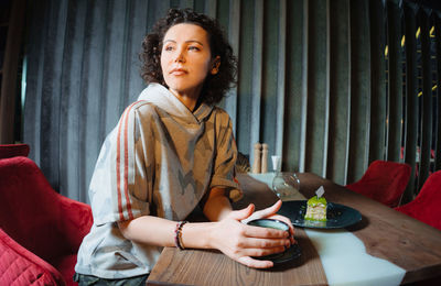 Teenage girl looking at camera while sitting on mobile phone