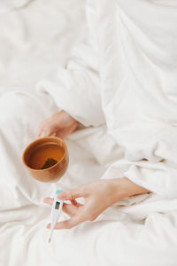 Midsection of woman holding coffee on bed