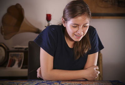 Happy teenage girl playing puzzle at home