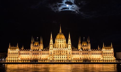 Illuminated hungarian parliament building by river at night