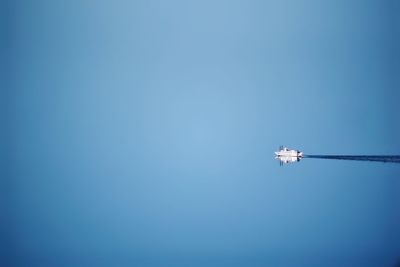 Low angle view of airplane flying against clear blue sky