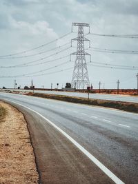 Electricity pylon by road against sky