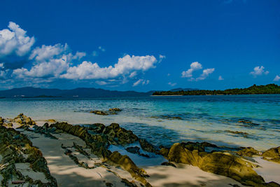 Rocky outcrops on the beach with island across the sea in the background